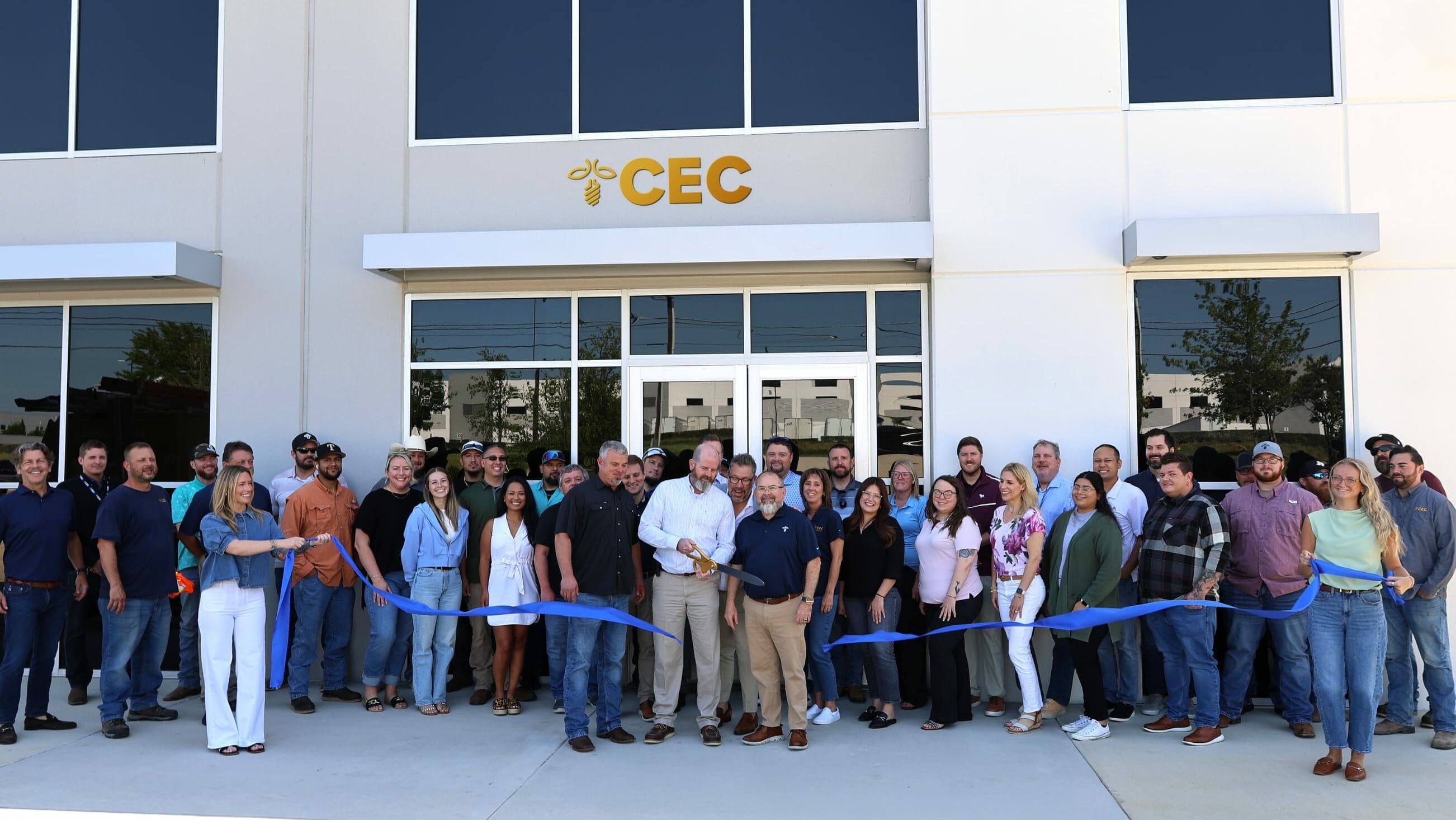 Group of people gathered outside the CEC Integrated Modular Solutions facility for a grand opening ribbon-cutting ceremony